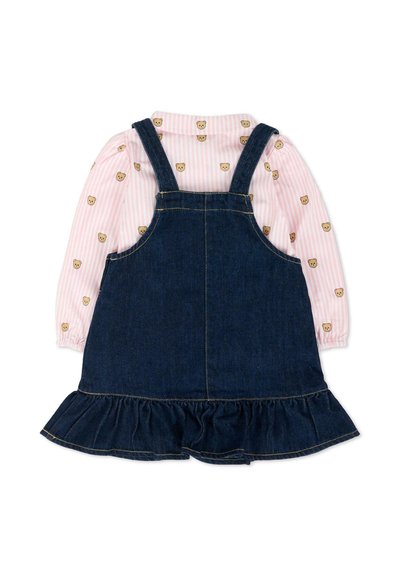 Robe salopette en denim avec ourlet à volants portée sur un chemisier rose à manches longues orné de petits visages d'oursons et de fines rayures.