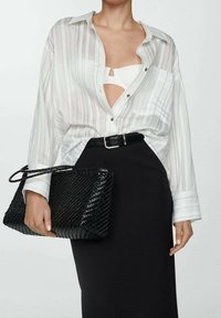Wit gestreepte blouse, zwarte riem, aansluitende zwarte rok en geweven zwarte clutch tas. Gelaagd fabric en gestructureerd ontwerp.