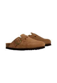 Sabots en daim marron avec une boucle en métal réglable, bout arrondi, semelle en liège et en caoutchouc, présentant une texture lisse et un design minimaliste.