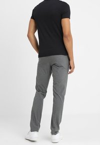 Grijze taps toelopende broek gemaakt van lichtgewicht stof, met een gladde afwerking. Gecombineerd met een zwarte strakke T-shirt en witte sneakers.
