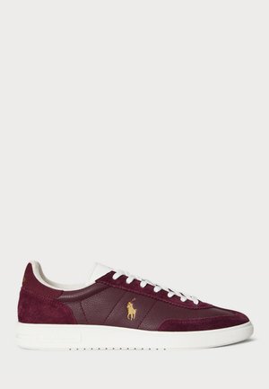 Sneaker bordeaux in suede e pelle texture, con dettagli bianchi, lacci piatti e un logo dorato in evidenza. Suola in gomma con motivo antiscivolo.