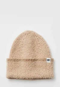Knit tan beanie hat with a folded brim, featuring a textured pattern and a tag on the side with a logo.