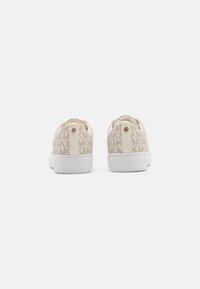 Beige patterned sneakers with white soles, featuring a logo accent and smooth textured material. Rounded back design with a low profile.