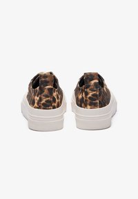 Leopard print slip-on shoes with a fabric upper, elastic side panels, and white rubber soles. Features a textured heel for grip.