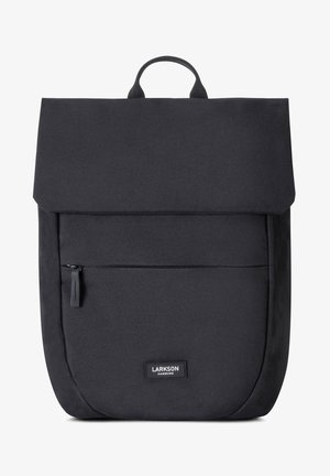 Black backpack made of fabric with a flap closure, featuring a front zip pocket and a logo patch. Smooth texture, rectangular shape.