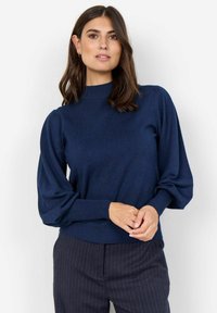 Maglione blu navy realizzato in tessuto morbido, caratterizzato da un collo alto e maniche a sbuffo, con polsini e orlo a coste per una vestibilità aderente.