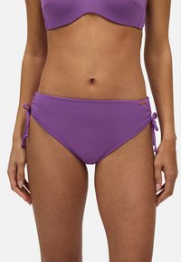 Bañador de bikini morado con una tela texturizada, que presenta lazos laterales ajustables y un sutil detalle de logo en la cadera derecha.