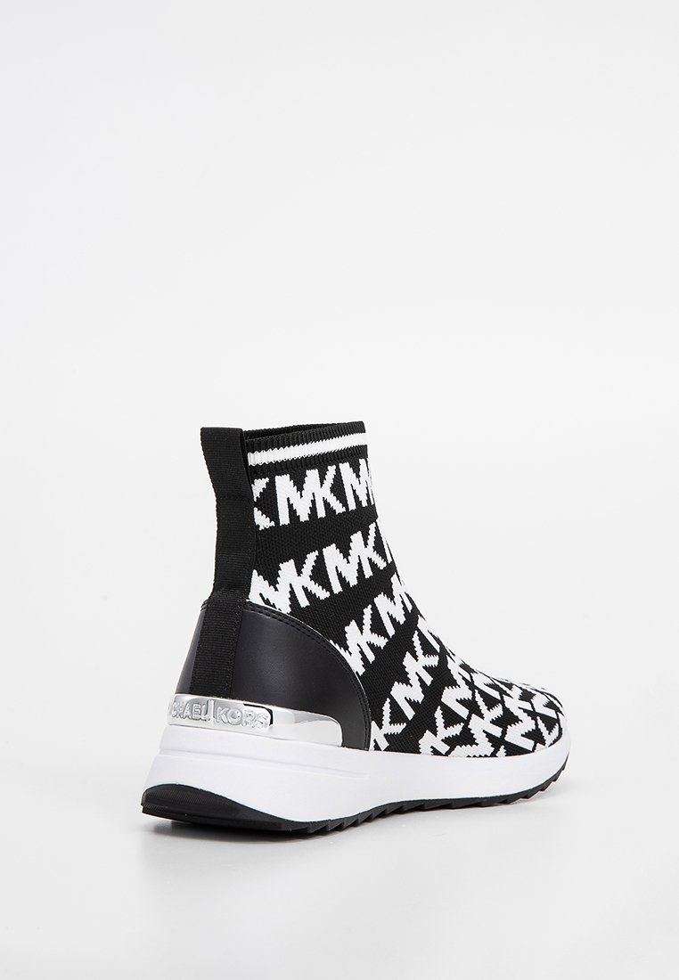 Botas de tobillo de punto en blanco y negro con un diseño, que presentan un tacón negro liso, suela blanca y un acento de logo metálico en la parte trasera.