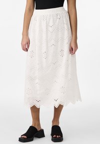Hvit midiskjørt med intrikate øylet broderier, bølget kant og elastisk midje. Kombinert med svarte åpne block heel sandaler.