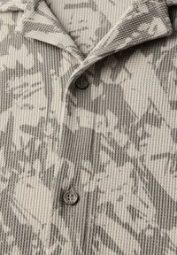 Grå och krämfärgad skjorta med knapp-up med ribbad textur, som har ett subtilt abstrakt mönster, insvängd krage och en enstaka knappdetalj.