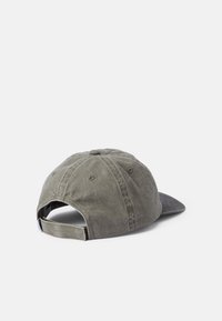 Khaki bawełniana czapka z zakrzywionym daszkiem, regulowany pasek z tyłu oraz haftowane detale na koronie i krawędzi daszka.