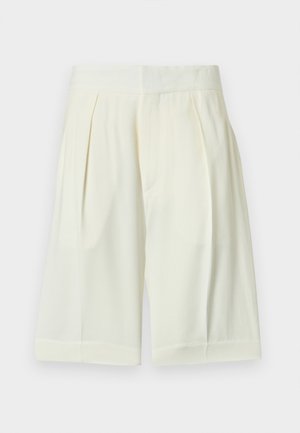 Pantalones cortos de cintura alta de color crema, confeccionados a medida con pliegues y una banda ancha en la cintura, hechos de tela ligera.