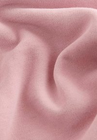 Blød, tekstureret stof i en lys rosa nuance, der har et strikket design med bløde folder, som viser dets fleksibilitet og glatte overflade.