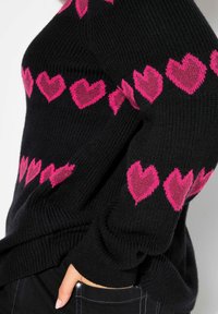 Maglione nero a maglia con un motivo di cuori rosa sulle maniche, con bordi a costine e una vestibilità comoda. Tessuto morbido e maniche lunghe.