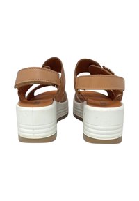 Sandali in pelle marrone con due cinturini regolabili e una robusta suola piatta bianca caratterizzata da scanalature orizzontali. Texture interna liscia.