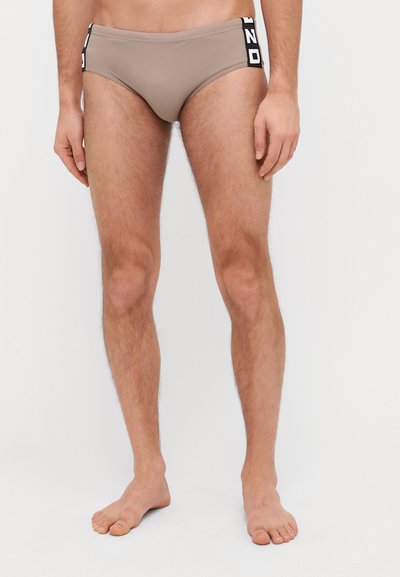 Slip da bagno da uomo in tessuto beige con taglio a vita bassa. Presenta accenti del logo in bianco e nero sul cinturino.