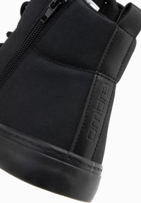 Černá vysoká teniska kombinuje semiš a hladkou kůži, má boční zip a vyražené logo.