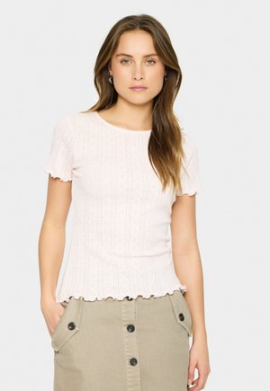Lichtroze top met korte mouwen, voorzien van een textuurdesign en een golvende rand, in een aansluitende snit, gecombineerd met een beige rok met knopen aan de voorkant.