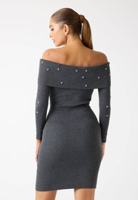 Szary sweterowy sukienka z dekoltem odkrywającym ramiona, długimi rękawami i ozdobnymi detalami, z małymi dekoracyjnymi kamieniami rozmieszczonymi w całej sukience.
