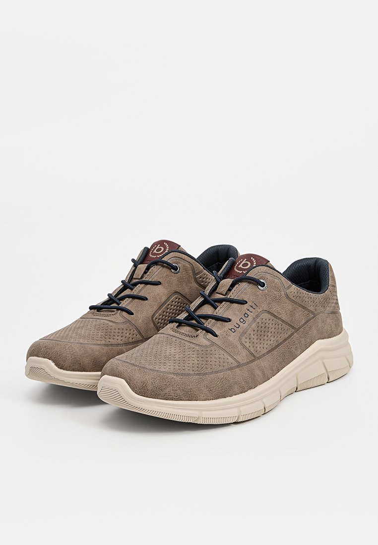 Un par de zapatillas Bugatti de ante marrón con cordones negros, suelas de goma gruesa beige y detalles perforados en los laterales y en la zona de los dedos.
