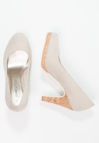 Beige suede high-heeled shoes with a cork accent heel. Rounded toe design with a smooth metallic insole. Minimalist style, clean lines.