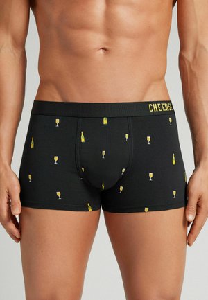 Boxer shorts negros de tejido suave, con un patrón de botellas y copas de champán amarillas, y una cinturilla que dice "¡SALUD!".