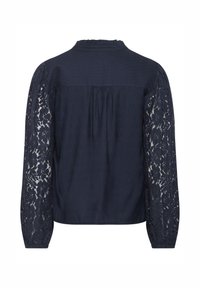 Blouse marine en tissu texturé, avec manches longues en dentelle et encolure à volants. Le dos est orné de plis pour plus de détail.