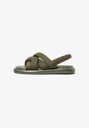 Olive green flat sandals with woven straps, rubber sole, and cushioned footbed. Features an open back and smooth texture.