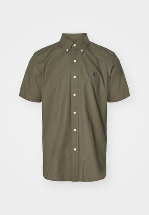 Oliven grønn kortermet skjorte med knapper, med krage, hvite knapper og en liten brodert logo på brystet. Teksturt bomullsstoff.