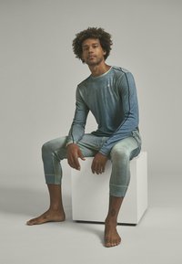 Blue gradient activewear set featuring a long-sleeve top and fitted leggings with contrast stitching. Material appears smooth and stretchy.