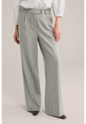 Grijze, visgraatpatroon wijde broek met plooien aan de voorkant, een knoopdetail in de taille en een gladde, gestructureerde stof. Gecombineerd met donkere schoenen.