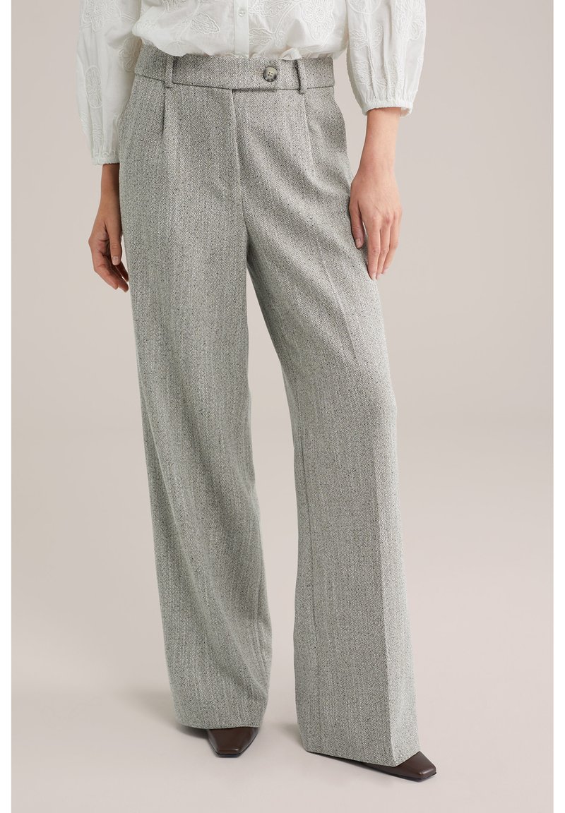 Grijze, visgraatpatroon wijde broek met plooien aan de voorkant, een knoopdetail in de taille en een gladde, gestructureerde stof. Gecombineerd met donkere schoenen.