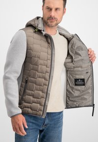 Gesteppten Jacke mit einem grauen isolierten Körper, hellgrauen Ärmeln und einer Kapuze. Das Innere ist mit glattem Stoff gefüttert und verfügt über eine Tasche.