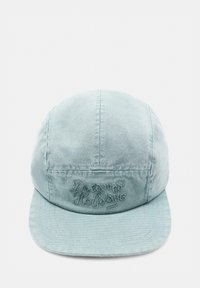 Casquette en tissu bleu clair avec une visière incurvée et un texte brodé subtil sur le devant, présentée sur un fond blanc uni.