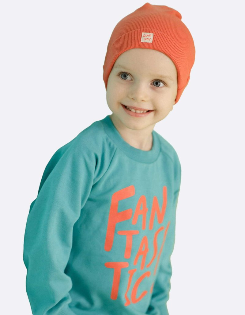 Turquoise sweatshirt met "FANTASTIC" in feloranje letters; geribde oranje beanie met een klein "GOOD DAY" label.