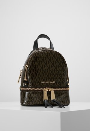 Petit sac à dos Michael Kors marron foncé avec motif logo MK sur toute la surface, fermetures éclair dorées et poignée en cuir noir sur fond blanc.
