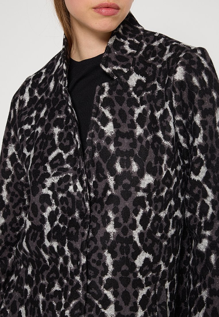 Manteau en imprimé léopard noir et gris, avec un col et une texture lisse. La conception comprend une coupe classique avec des coutures visibles.
