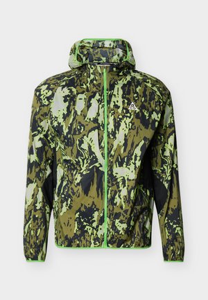 Ľahká bunda s kapucňou s abstraktným maskovacím vzorom v zelenej a čiernej farbe a predným zipsom, s malým bielym trojuholníkovým logom na hrudi.