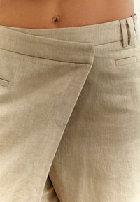 Beige, teksturerade linbyxor med bred midjeband, med en frampåveck och två sidofickor, designade i en avslappnad passform.
