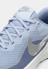Svijetloplave Nike tenisice za trčanje s mrežastom teksturom, odgovarajućim vezicama, srebrnim swoosh logotipom i uljepšanom bijelom potplatom.