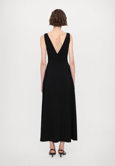 Zwart mouwloos jurk met een V-rug ontwerp, vloeiende maxi-silhouet, zachte stof en subtiele details bij de hals en de rug.