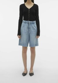 Cardigan negro de canalé de manga larga con escote en V y cierre de botones, combinado con shorts de mezclilla azul claro con cintura ajustable. Bailarinas negras.