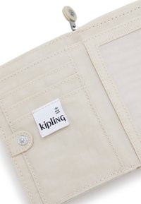 Portafoglio beige sicuro RFID con più scomparti per carte, chiusura a scatto e un prominente etichetta con logo Kipling. Tessuto testurizzato con dettagli di cucitura.