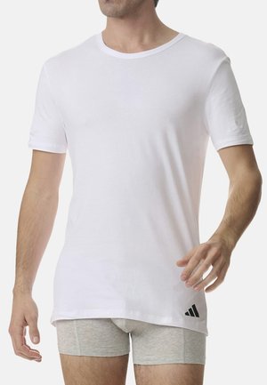 Kurzärmliges, weißes Baumwoll-T-Shirt mit Rundhalsausschnitt und einem schwarzen Adidas-Logo-Accento nahe dem Saum. Weicher Stoff und lässige Passform.