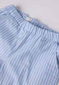 Vaaleansininen raidoitettu kangas, jossa on joustava vyötärö ja napitusyksityiskohta. Raidat ovat vaakasuoria ja niissä on hienovaraisia valkoisia viivoja tekstuurin luomiseksi.