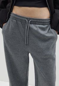 Graue Jogginghose aus weichem, strukturiertem Stoff. Mit elastischem Bund und verstellbaren Kordeln sowie seitlichen Taschen.