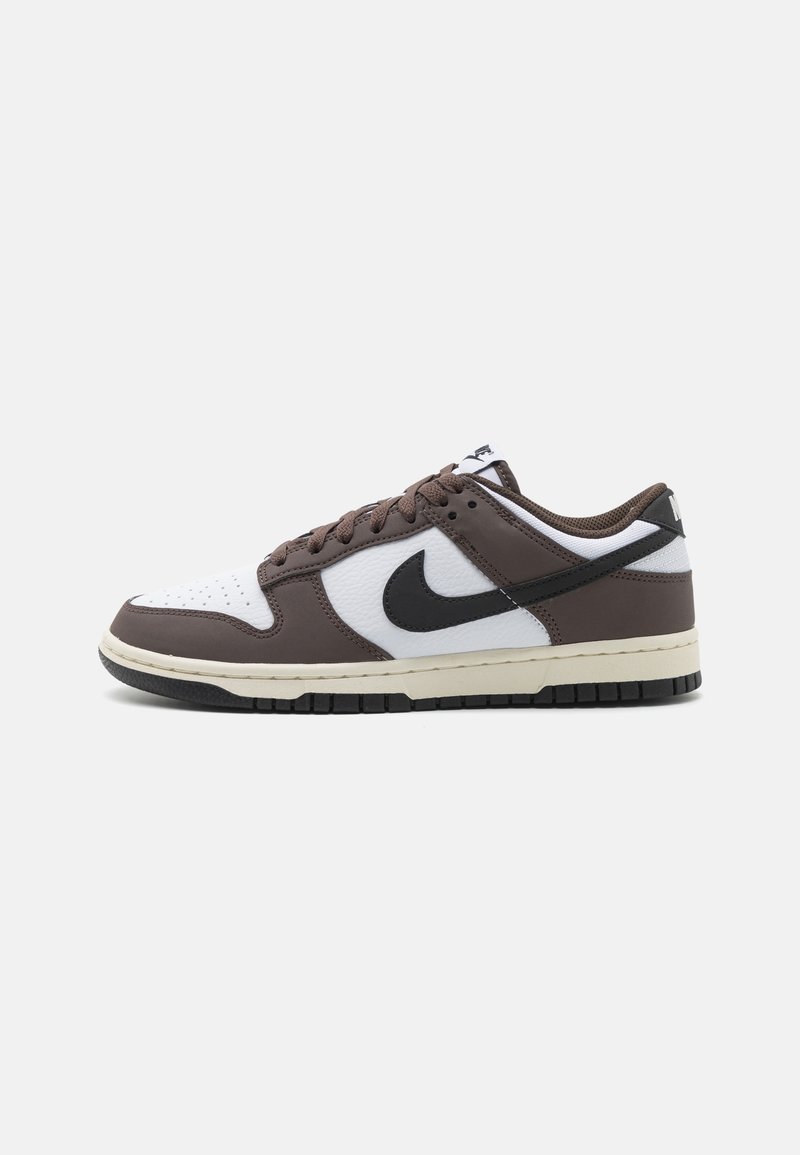 Teniska Nike Dunk Low s hnědým a bílým koženým svrškem, černým logem Swoosh a strukturovanou gumovou podrážkou.