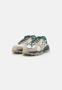 Sport shoes featuring a mix of suede and synthetic materials. Pale beige and grey with green accents, and a rugged sole for traction.