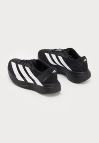 Paar schwarze Adidas-Laufschuhe mit weißen Streifen und dicken Sohlen, schräg dargestellt, um Seiten- und Rückansichten auf einfarbigem Hintergrund zu zeigen.
