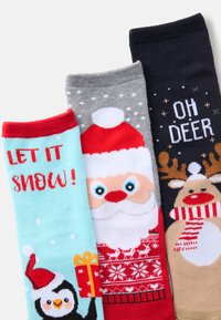 Kolm paari sokke: helesinine pingviiniga ja tekstiga, hall Jõuluvana kujutisega, tumesinine päkapiku ja fraasiga "OH DEER." Tekstureeritud kudumine.